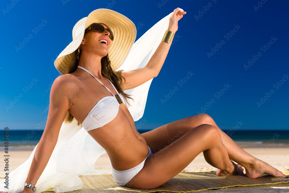 Attraktive Frau im Bikini lacht die Sonne am Strand an