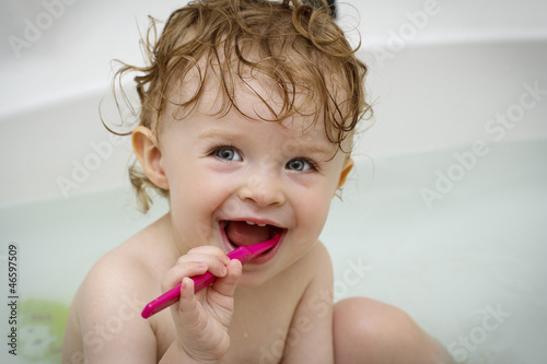 Little baby cleaning teeth in the bath