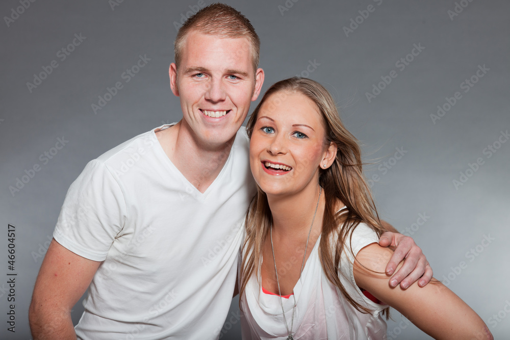 Young couple together in love against grey wall. Studio shot.