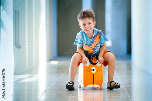 Cute happy boy with a suitcase at airport