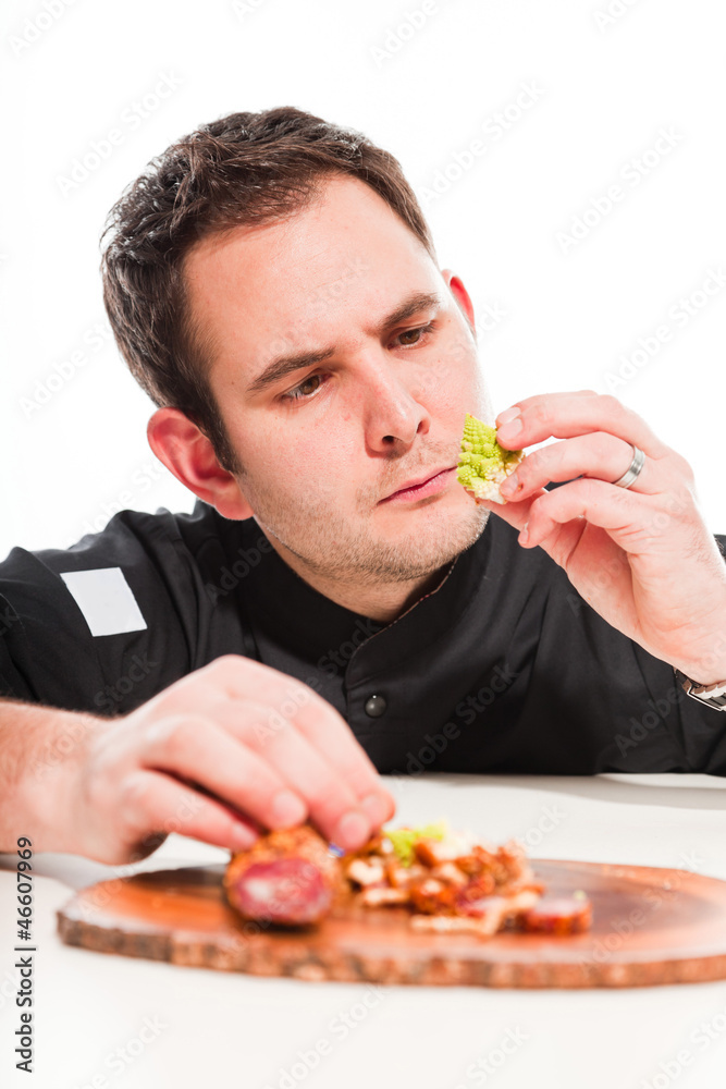 Male cook with black jacket preparing raw ingredients.