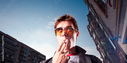 Young man smoking a cigarette on a city street