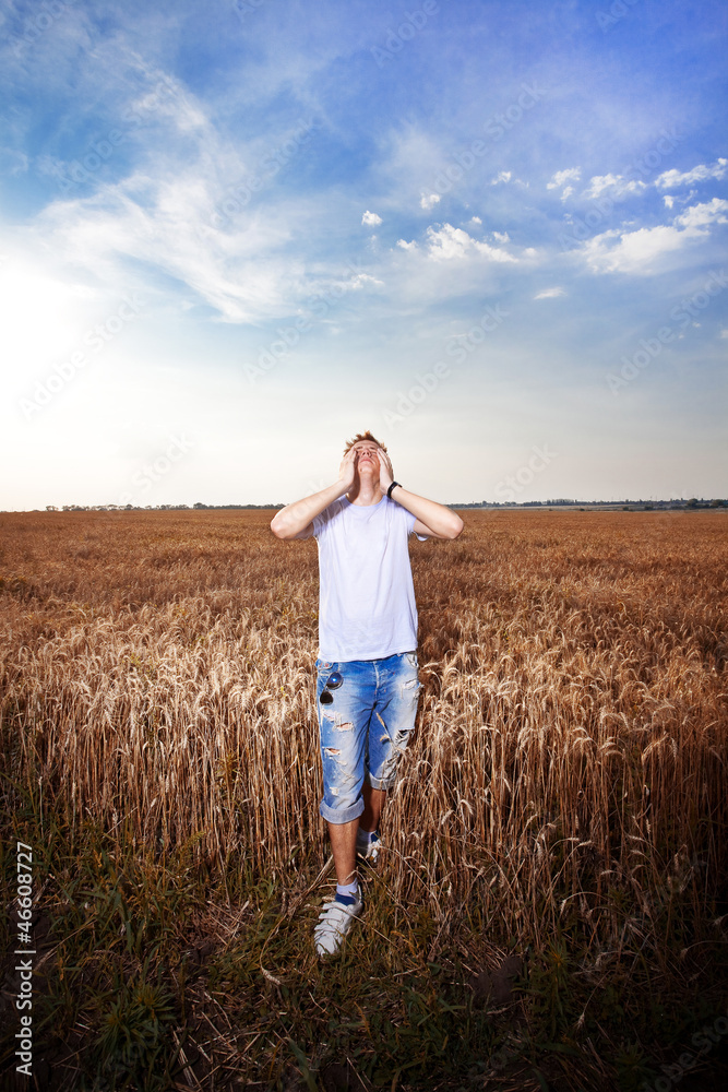 Happy man standing with closed arms on a wheat field