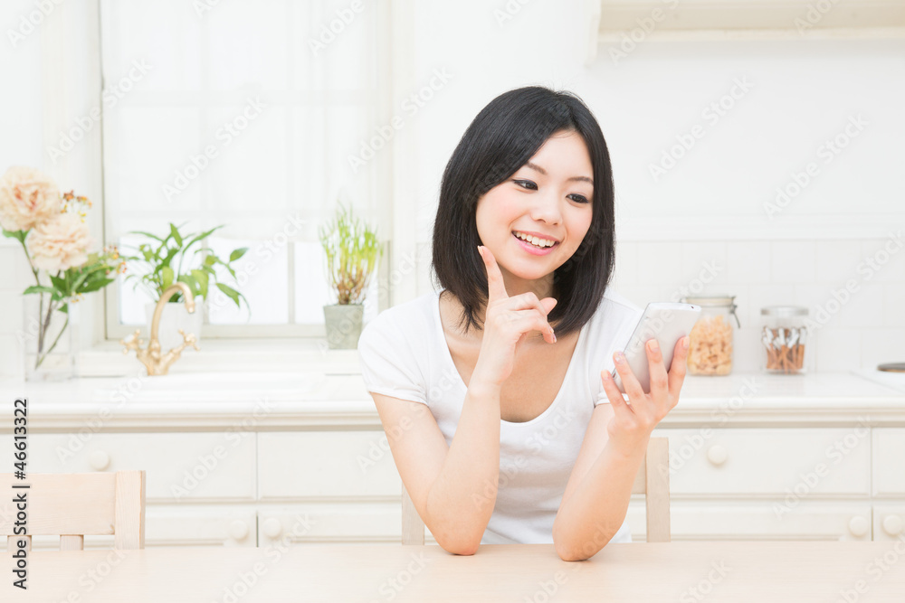 キッチンでスマートフォンを見る女性 キッチンでスマートフォンを見る女性