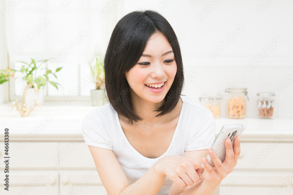 キッチンでスマートフォンを見る女性