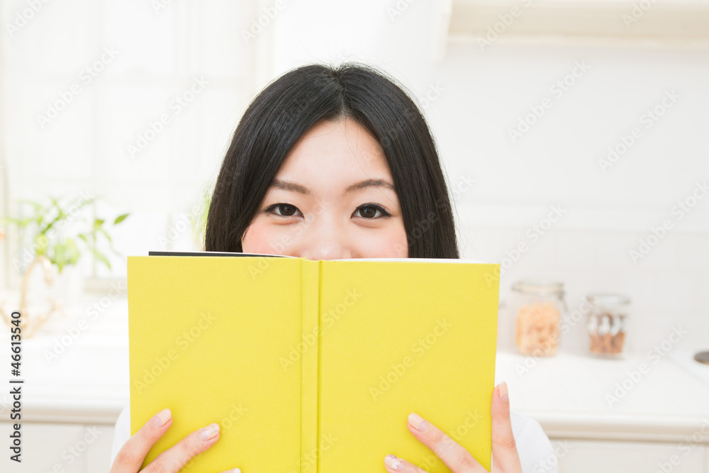 キッチンで本を読む女性