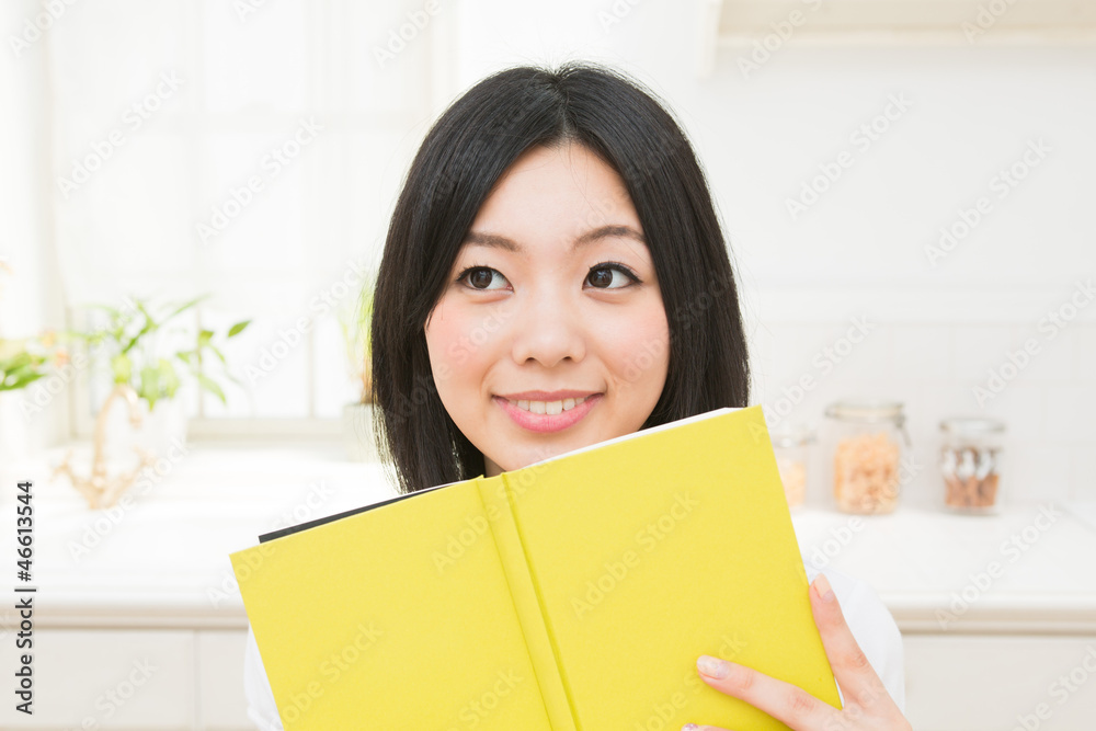 キッチンで本を読む女性