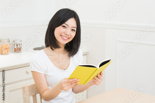 キッチンで本を読む女性