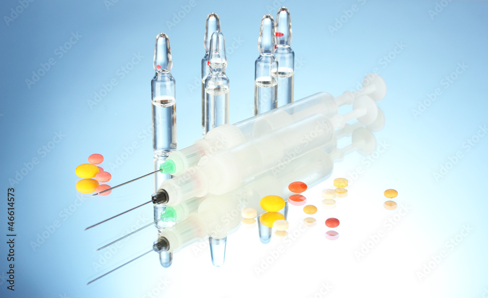 syringes monovet, ampoules and pills on blue background