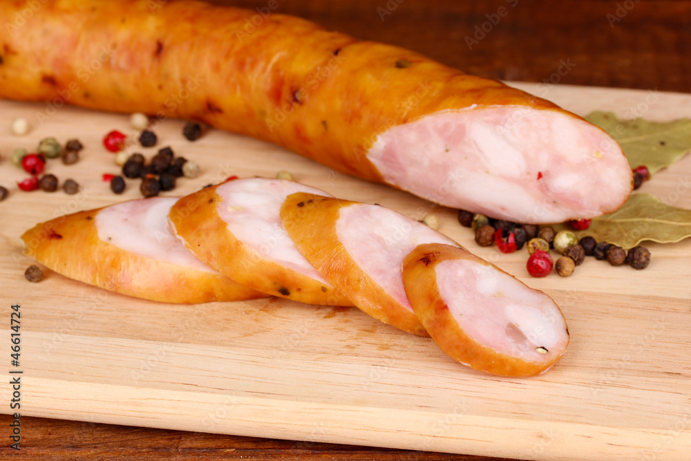 Tasty sausage on chopping board on browm background Tasty sausage on chopping board on browm background
