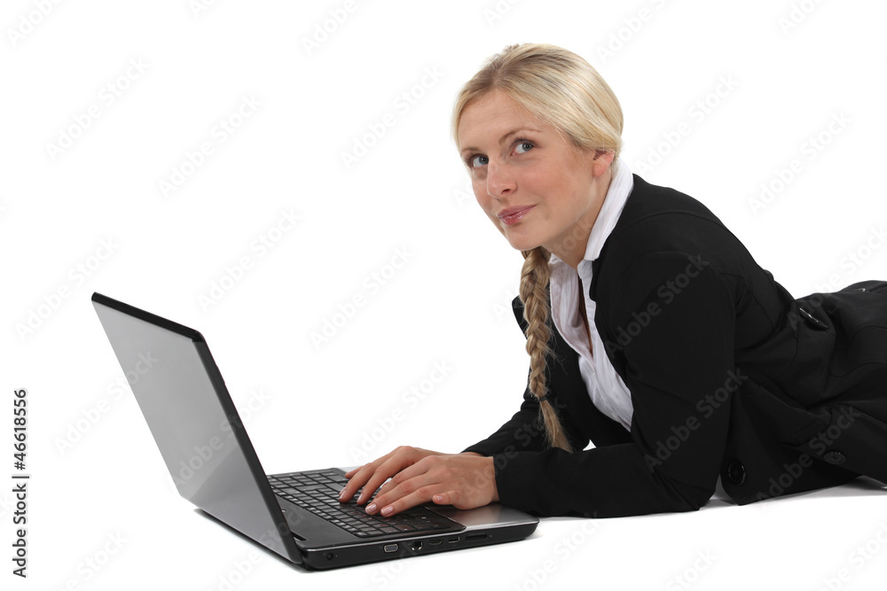 Blond businesswoman laying on front and typing on laptop Blond businesswoman laying on front and typing on laptop
