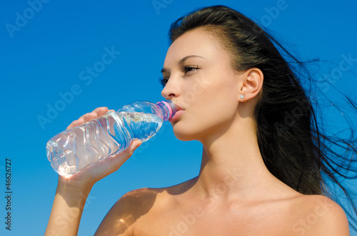 Beautiful brunette girl drinking from a bottle of water