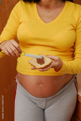 Mujer embarazada comiendo pan con crema de chocolate. photo