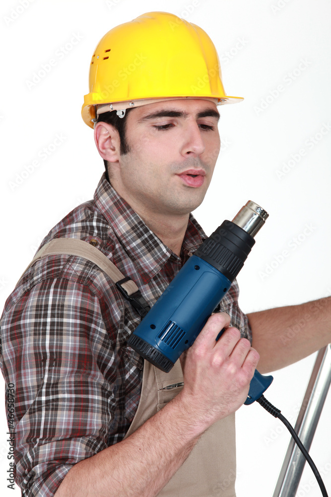 Tradesman blowing on his screw gun