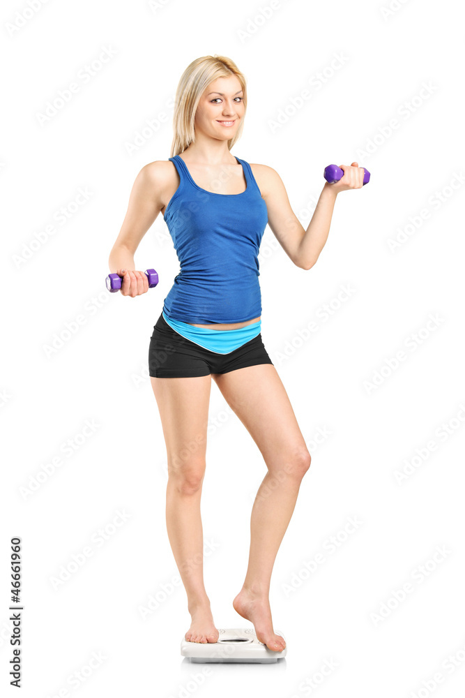 Smiling female standing on a weight scale and holding a weights Smiling female standing on a weight scale and holding a weights