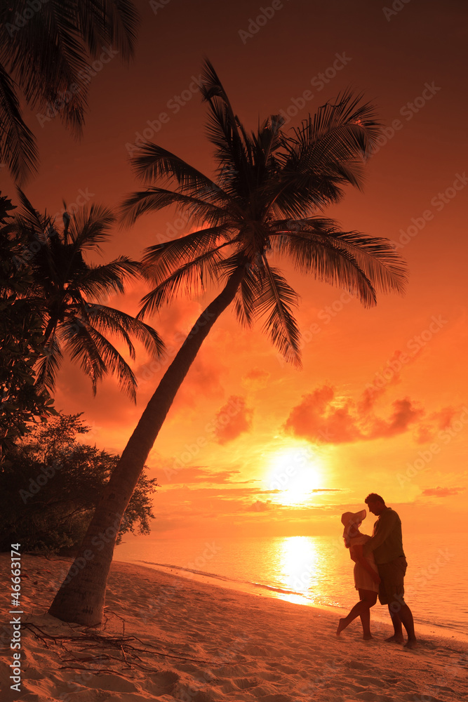 Couple kissing at beach with sunset in the background, Maldives