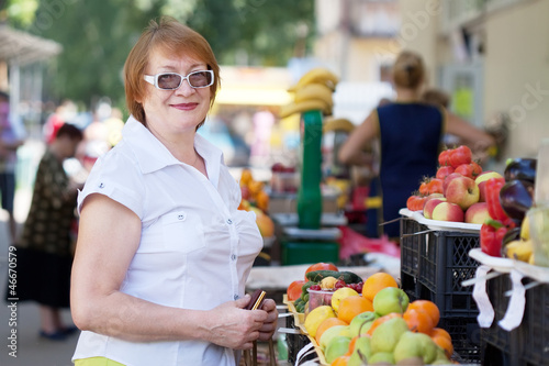 Mature woman  chooses fruits photo