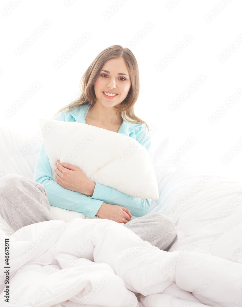 A young and happy brunette woman relaxing in a white bed A young and happy brunette woman relaxing in a white bed