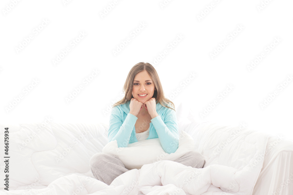A young and happy brunette woman relaxing in a white bed A young and happy brunette woman relaxing in a white bed
