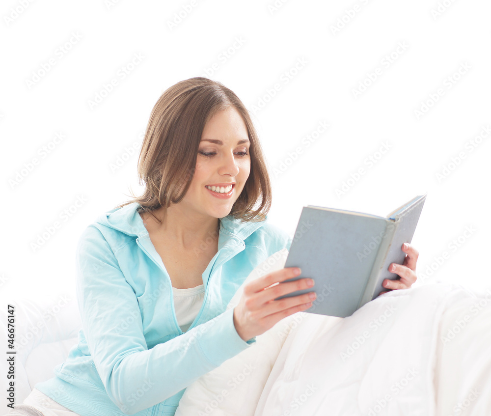 A young brunette woman reading a book on a white sofa A young brunette woman reading a book on a white sofa