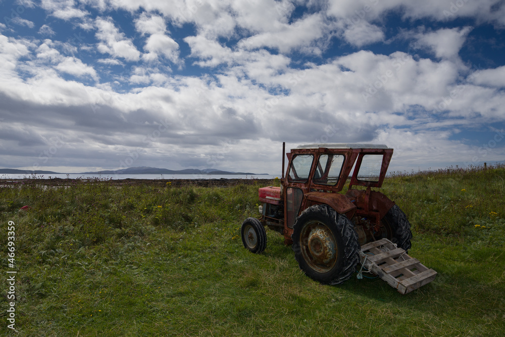 Obraz premium Rusty old red tractor by the sea