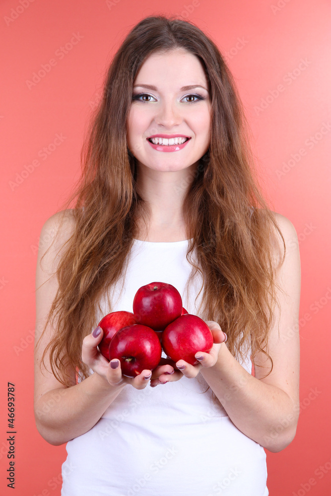 Beautiful woman with apples on pink background