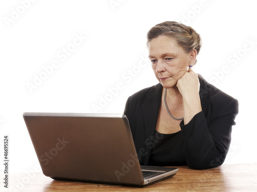 Mature woman sitting by table working on notebook computer