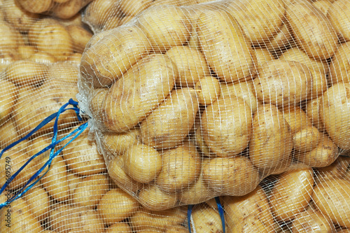 White potatoes in mesh bags on the market.