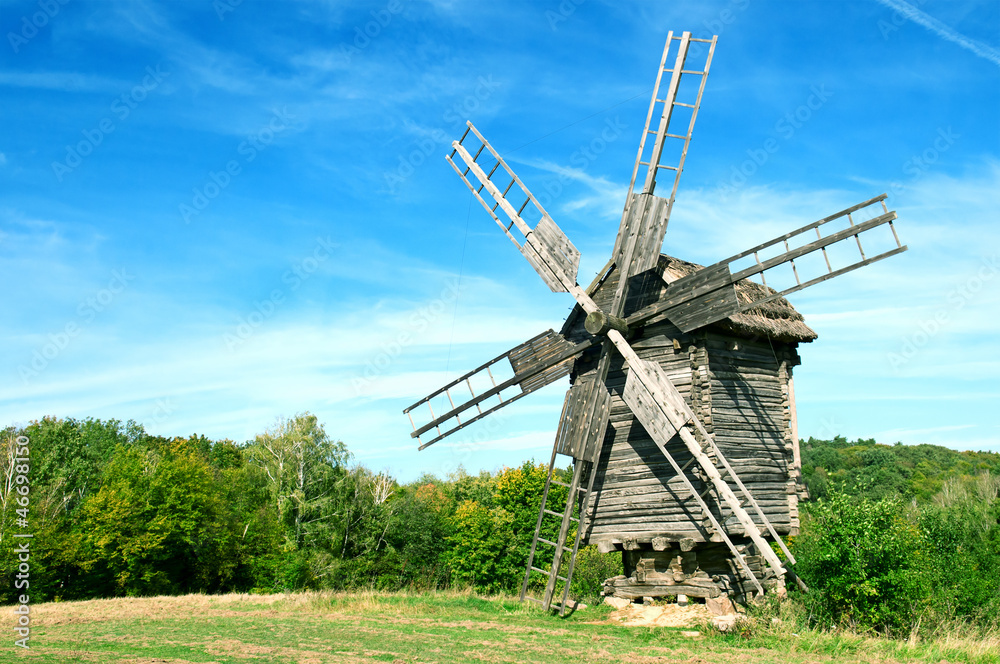 Old wooden windmill in the background of the autumn forest