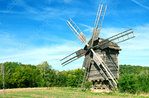 Old wooden windmill in the background of the autumn forest