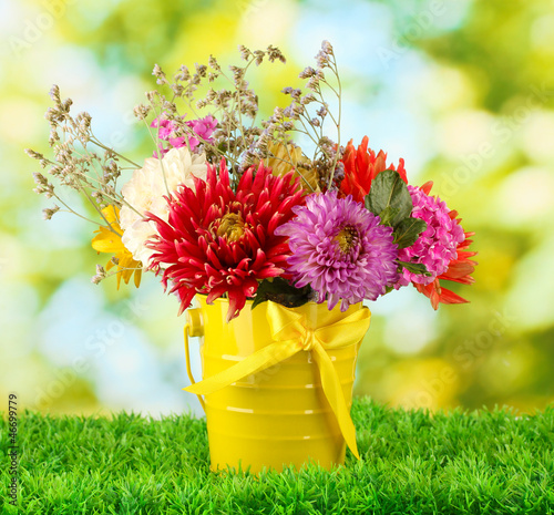 Bright yellow bucket with flowers on green background