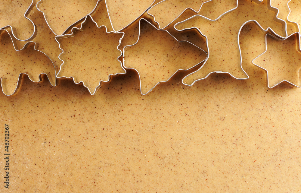 Christmas cookie cutters over gingerbread dough Christmas cookie cutters over gingerbread dough
