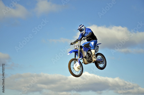 Flight of biker motocross against the blue sky and clouds