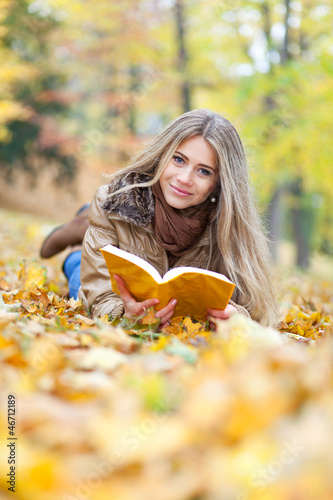 Young woman reading lying on leaves