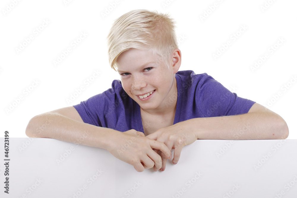 Blonder Junge schaut lächelnd über ein leeres Plakat Blonder Junge schaut lächelnd über ein leeres Plakat