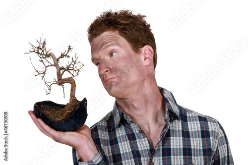 man covered with dirt holding a dead plant photo