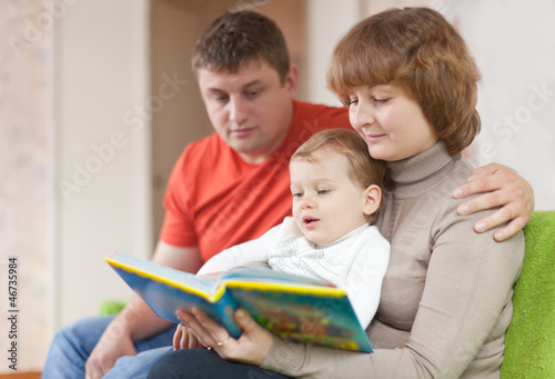  parents with child looks the book