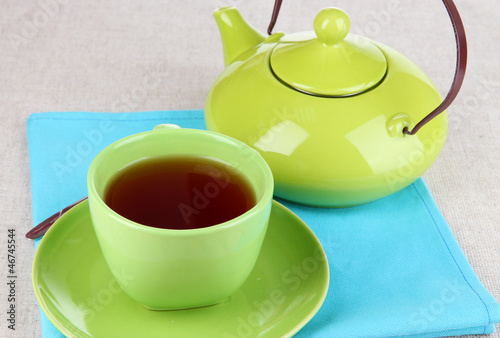 Top view of cup of tea and teapot on tablecloths