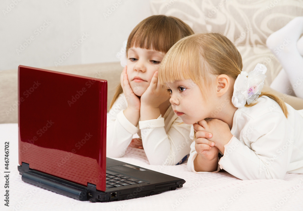 Two little girls are with a laptop and a credit card Two little girls are with a laptop and a credit card