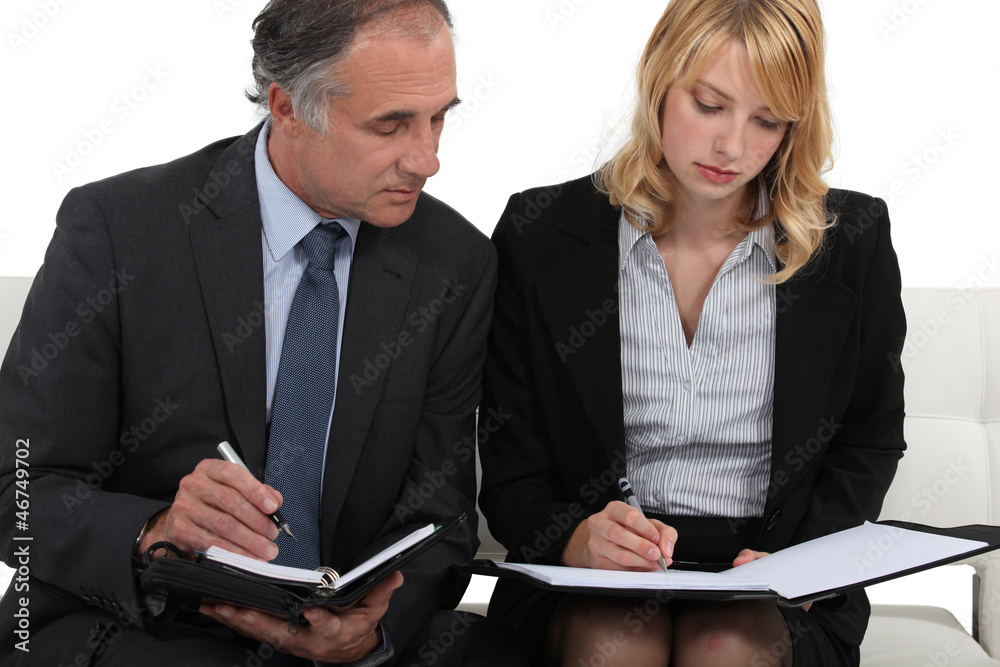 CEO and assistant checking appointments in their diaries CEO and assistant checking appointments in their diaries