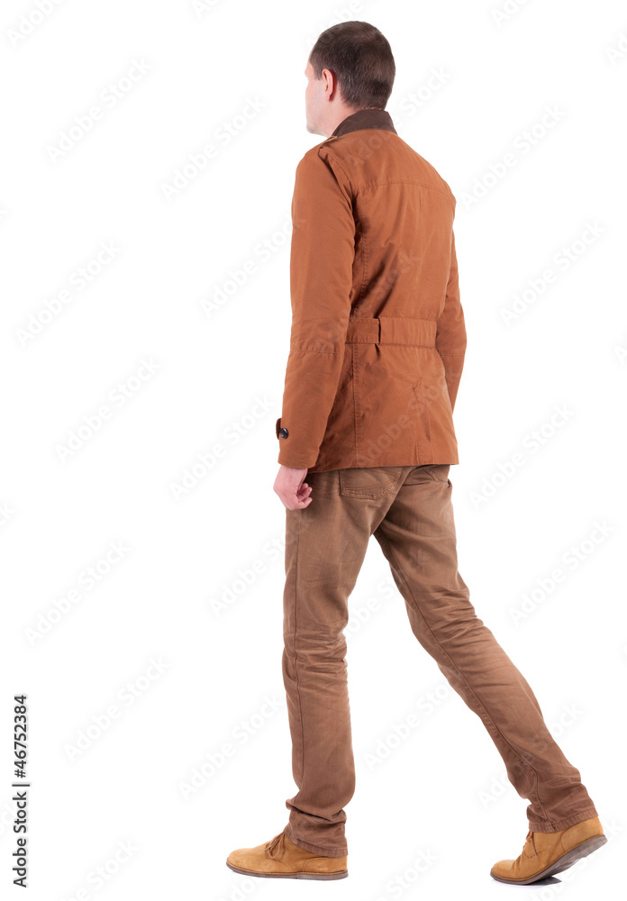 Naklejka premium Back view of walking handsome man in jeans and jacket.
