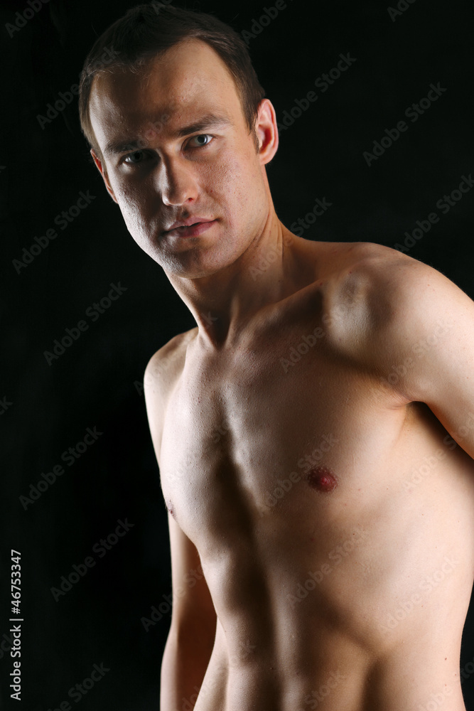 Fototapeta premium Portrait of a naked muscular man, isolated on black background