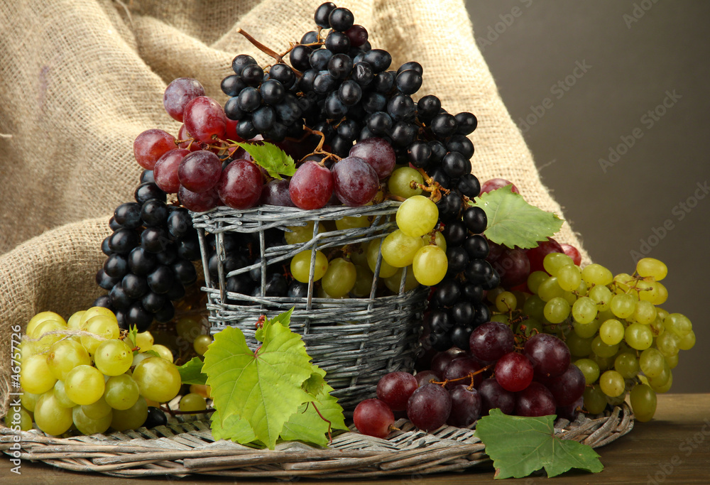 assortment of ripe sweet grapes in basket, on grey background assortment of ripe sweet grapes in basket, on grey background