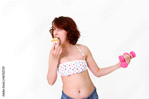 Young woman with dumbbells and cake photo