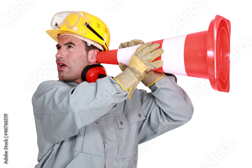 Laborer listening carefully through a traffic cone photo