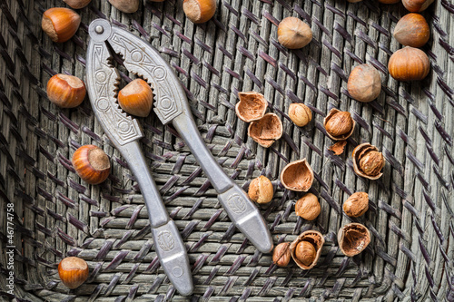 Closeup hazelnuts with nutcracker in old basket