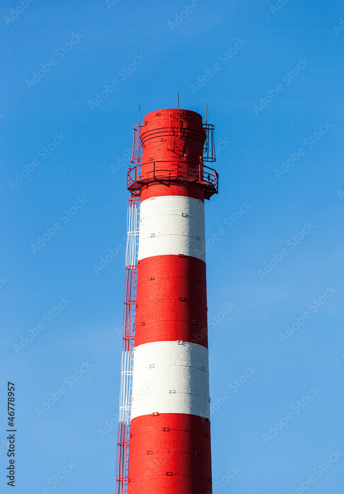 Red and white factory chimney against blue sky Red and white factory chimney against blue sky