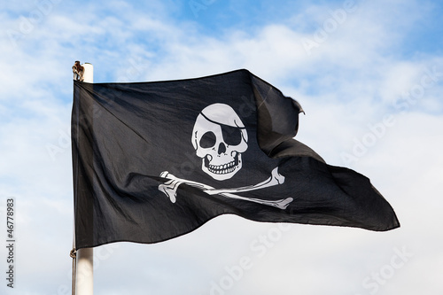 Waving Pirate flag isolated on blue sky photo