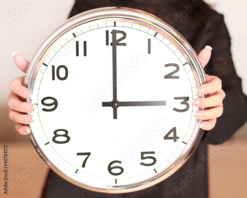 Frau hält rießige Uhr in der Hand