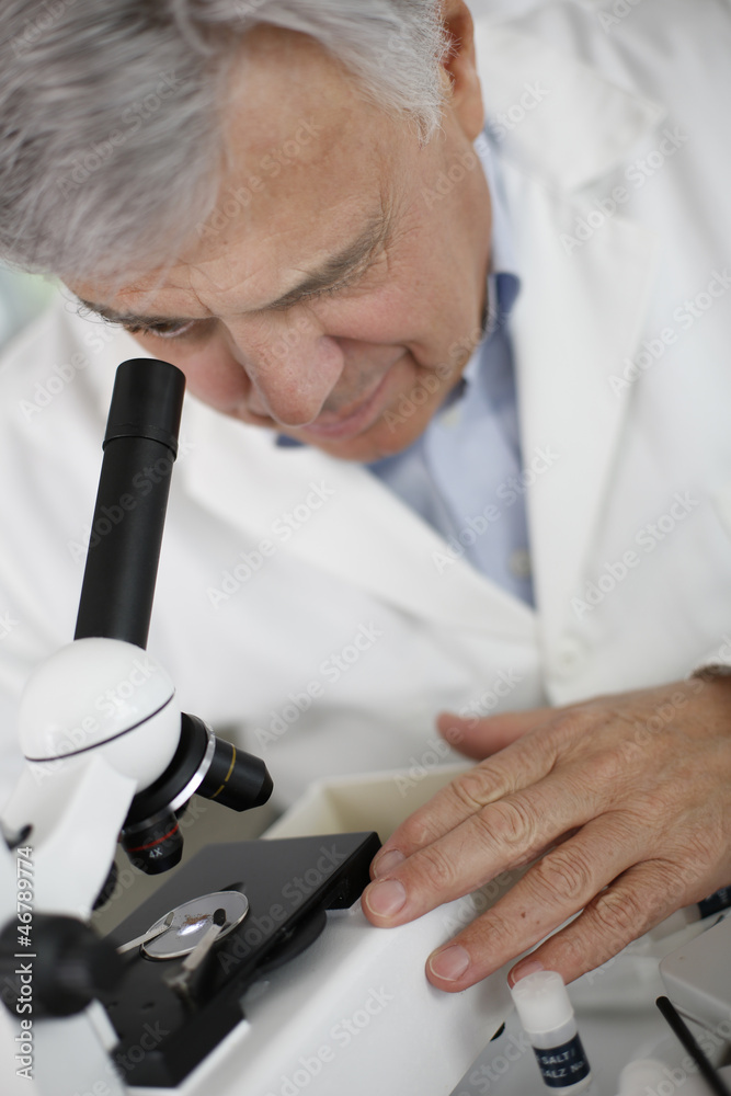 Scientist in lab looking through microscope lens Scientist in lab looking through microscope lens